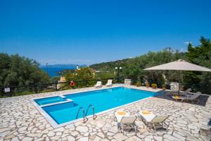 a swimming pool with chairs and an umbrella at Villa Aphrodite in Meganisi