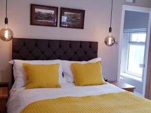 a bedroom with a bed with yellow sheets and two lights at The Bowes Hotel in Bardon Mill