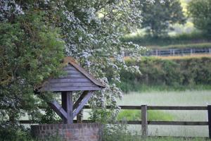 uma casa de pássaros de madeira ao lado de uma cerca em The Chiltern Lodges at Upper Farm Henton em Chinnor