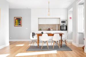 a white kitchen with a wooden table and white chairs at JOIVY Marvelous 3-bed home with astonishing view and terrace, nearby St George Castle in Lisbon
