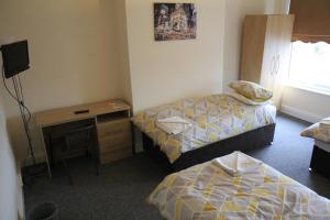 um quarto com 2 camas, uma secretária e uma televisão em Clifton arms em Liverpool