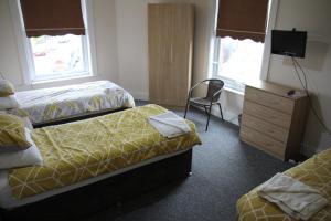 una habitación de hotel con 2 camas y una silla en Clifton arms, en Liverpool