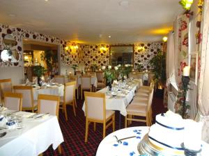 a restaurant with white tables and chairs and flowers at The Commercial Hotel in Tarland