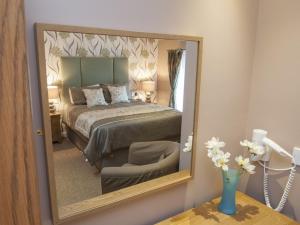 a mirror reflecting a bedroom with a bed and a chair at The Commercial Hotel in Tarland