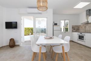 een keuken en eetkamer met een witte tafel en stoelen bij Chalet a 150m de la playa y piscina privada in Cala'n Bosch
