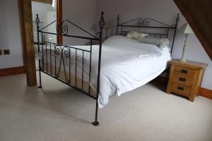 a bedroom with a black bed with white sheets at The Dairy at High House in Tintinhull