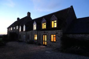 una antigua casa de piedra con sus luces encendidas en The Dairy at High House, en Tintinhull