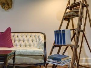 a room with a couch and a ladder with books at The English Merchant's Inn in Waxahachie