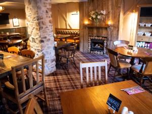 a restaurant with tables and chairs and a fireplace at The Exeter Inn in Bampton