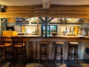 un bar con taburetes de madera en un restaurante en The Exeter Inn, en Bampton
