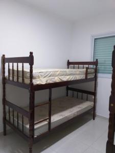 two bunk beds in a room with a window at Apartamento Temporada pé na areia in Mongaguá