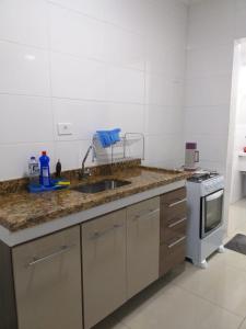 a kitchen with a sink and a stove at Apartamento Temporada pé na areia in Mongaguá