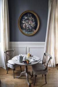 a table and chairs with a painting on the wall at Château Ormes de Pez in Saint-Estèphe