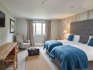 a hotel room with two beds and a chair at The Pig Shed Motel in Castle Acre