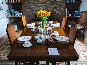 - une table en bois avec des fleurs et de la vaisselle dans l'établissement Pengelly Farmhouse B&B, à Truro