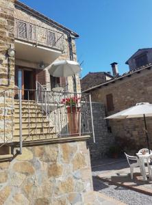 une maison en pierre avec des escaliers et un parasol dans l'établissement Beautiful apartment with exclusive garden and terrace, à Monteverdi Marittimo