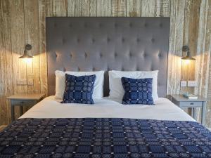 a bedroom with a large bed with blue pillows at The Pig Shed Motel in Castle Acre