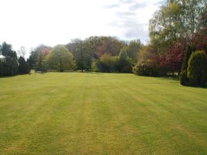 a large grass field with trees in the background at Park Hill Hotel in Lowestoft