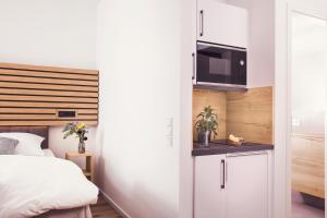 1 dormitorio con 1 cama y cocina con microondas en ZÄHLWERK Apartments, en Pfaffenhofen an der Ilm