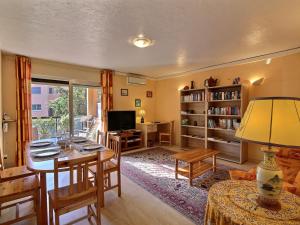 a living room with a table and chairs and a television at Paradisier Apartment Mougins in Mougins