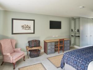 a bedroom with a bed and a chair and a television at The Pig Shed Motel in Castle Acre