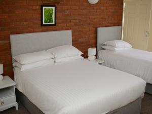 a bedroom with two beds and a brick wall at Park Hill Hotel in Lowestoft