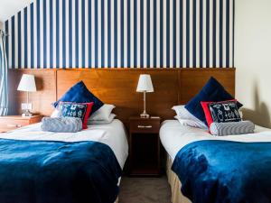 two beds in a hotel room with blue pillows at Pier 36 in Donaghadee