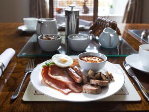 a plate of breakfast food with sausage and eggs on a table at Pengelly Farmhouse B&B in Truro +20 photos