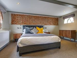 ein Schlafzimmer mit einem Bett und einer Ziegelwand in der Unterkunft The Ingham Swan in Stalham