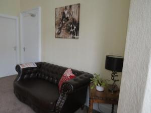 a black leather couch in a living room with a table at The Heidi Bed & Breakfast in Southport