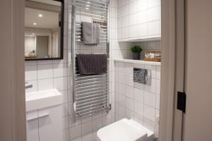 uma casa de banho em azulejos brancos com um WC e um lavatório em The Hideaway em Southampton