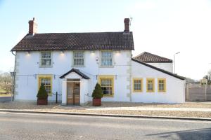 a white house with yellow windows on a street at The Mendip Inn in Binegar