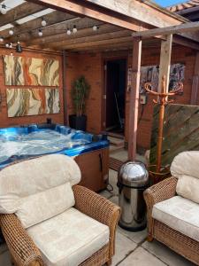 a hot tub on a patio with two chairs at The Mayfair Lodge & Family Suite in Hartlepool