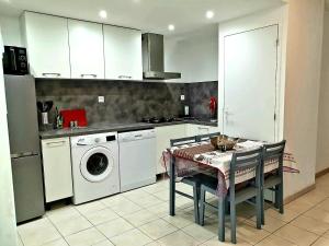 a kitchen with a washing machine and a table with chairs at Gite libecciu in Pietracorbara