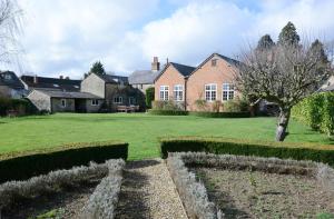 una grande casa con un giardino verde con cespugli di The Old School a Bicester