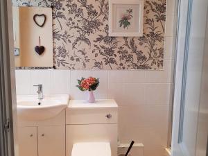 ein Badezimmer mit einem Waschbecken und einer Vase aus Blumen in der Unterkunft The Pavilion Guest House in Millom