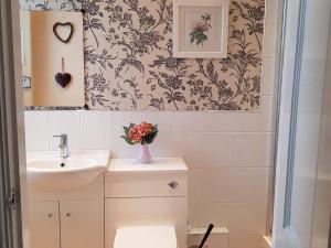 un bagno con lavandino e vaso di fiori di The Pavilion Guest House a Millom