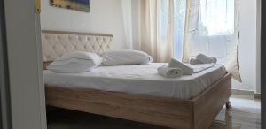 Una cama con almohadas blancas y una ventana. en Redsun Apartment, en Vlorë