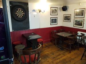 a dining room with two tables and a dartboard on the wall at The Railway Inn in Dawlish