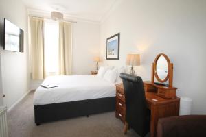 a bedroom with a bed, chair, desk and a television at Andover House Hotel & Restaurant - Adults only in Great Yarmouth