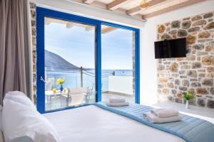 a bedroom with a large window with a view of the ocean at Molos Apartments in Loutro