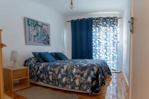 a bedroom with a bed and a blue curtain at Caparica Beach House Holiday Home in Costa da Caparica