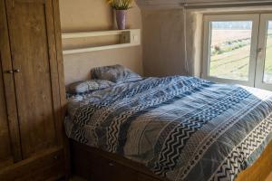 Ce lit se trouve dans une petite chambre dotée d'une fenêtre. dans l'établissement Vakantiewoning De Wilg - rustig gelegen, à Grammont
