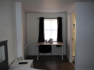 Cette chambre dispose d'un bureau et d'une fenêtre avec une chaise. dans l'établissement The Swan Inn, à Southampton