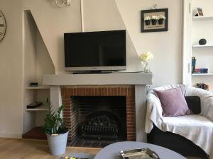sala de estar con chimenea y TV de pantalla plana en L'Appartement R Postel (4/6 Pers), en Honfleur