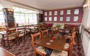 uma sala de jantar com mesas e cadeiras de madeira em Trecastell Hotel em Amlwch