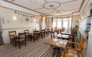 a restaurant with wooden tables and chairs in a room at Trecastell Hotel in Amlwch