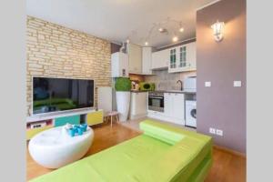 a living room with a green couch and a large tv at VERY CENTRAL DISNEYLAND apartment in Serris