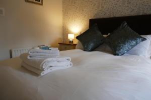 a bedroom with a white bed with towels and pillows at The Victoria in Malham