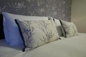 1 cama con almohadas blancas y papel pintado con motivos florales en The Victoria en Malham